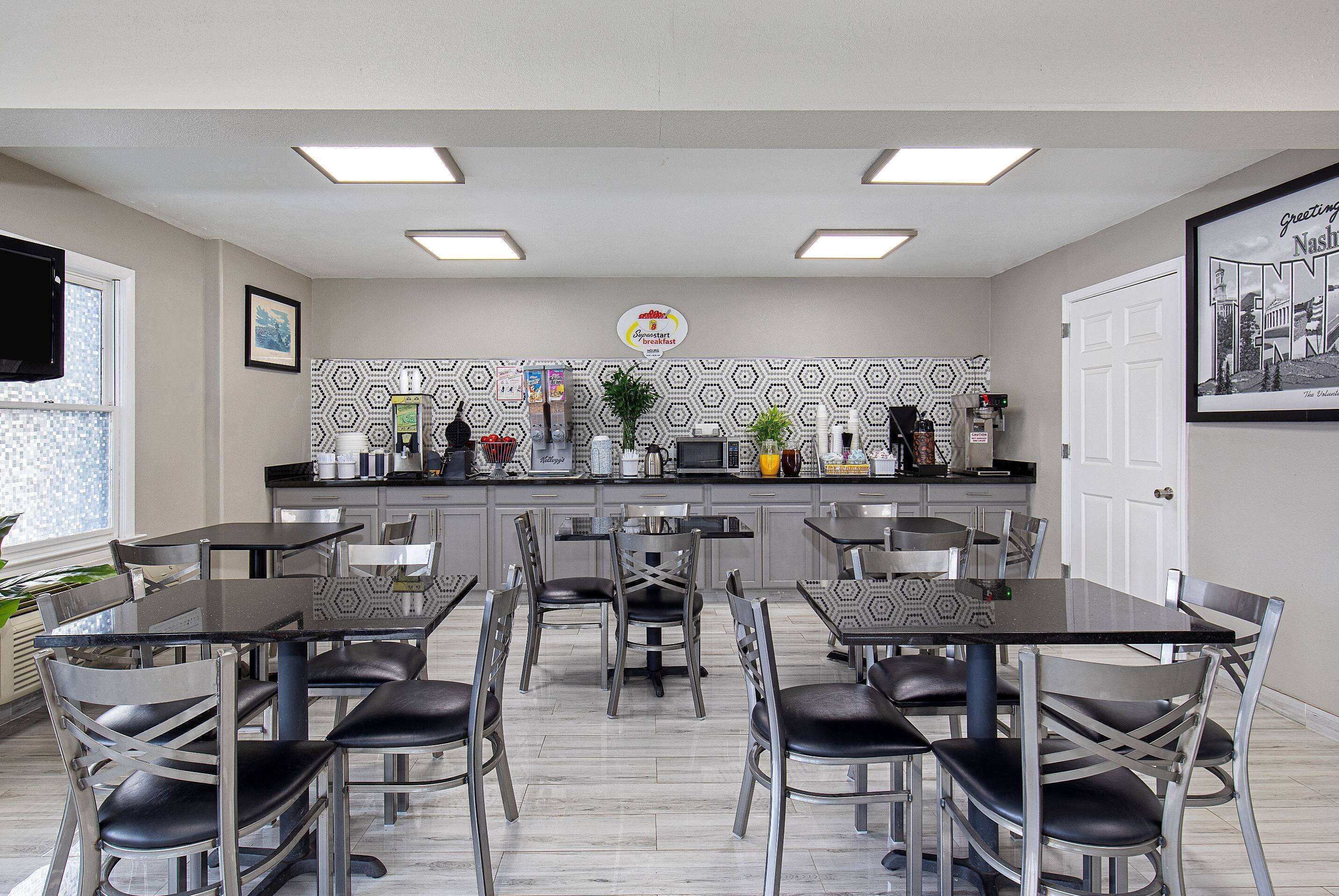 Una cocina moderna con barra americana, máquina de café y cartel que anuncia servicio de desayuno.