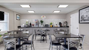 Una cocina moderna con barra americana, máquina de café y cartel que anuncia servicio de desayuno.