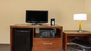 A hotel room with a wooden desk, a television, a microwave, a refrigerator, and a lamp. - Super 8 by Wyndham Nashville West (Nashville)