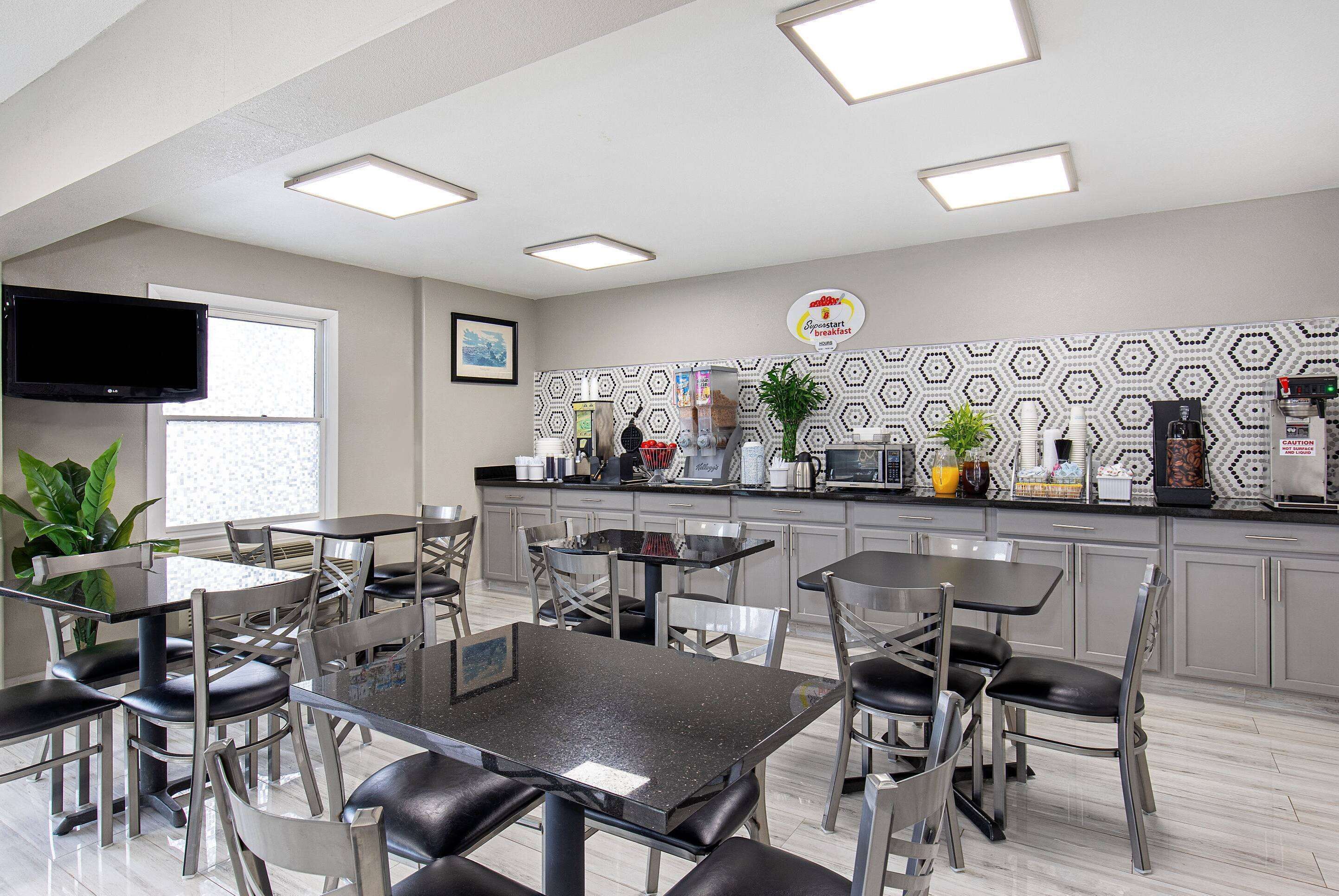 A modern kitchen with a coffee station, dining tables, and chairs.