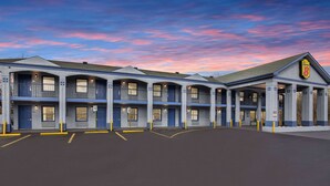 A motel with a row of rooms, a covered parking area, and a distinctive sign on the building. - Super 8 by Wyndham Nashville West (Nashville)
