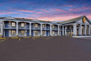 A motel with a row of rooms, a covered parking area, and a distinctive sign on the building.