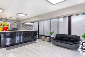 A modern reception area with a marble counter, a black leather sofa, and large windows.