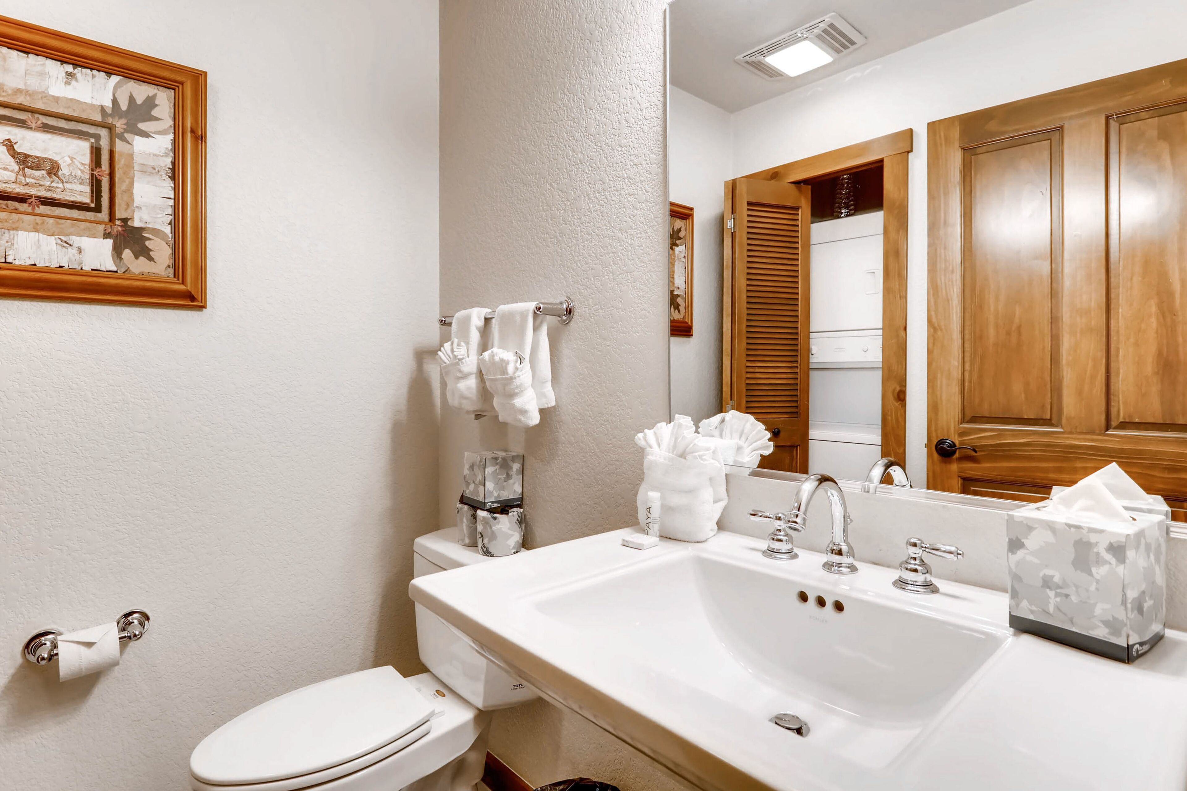 Un baño con un lavabo blanco, inodoro y una puerta de madera.