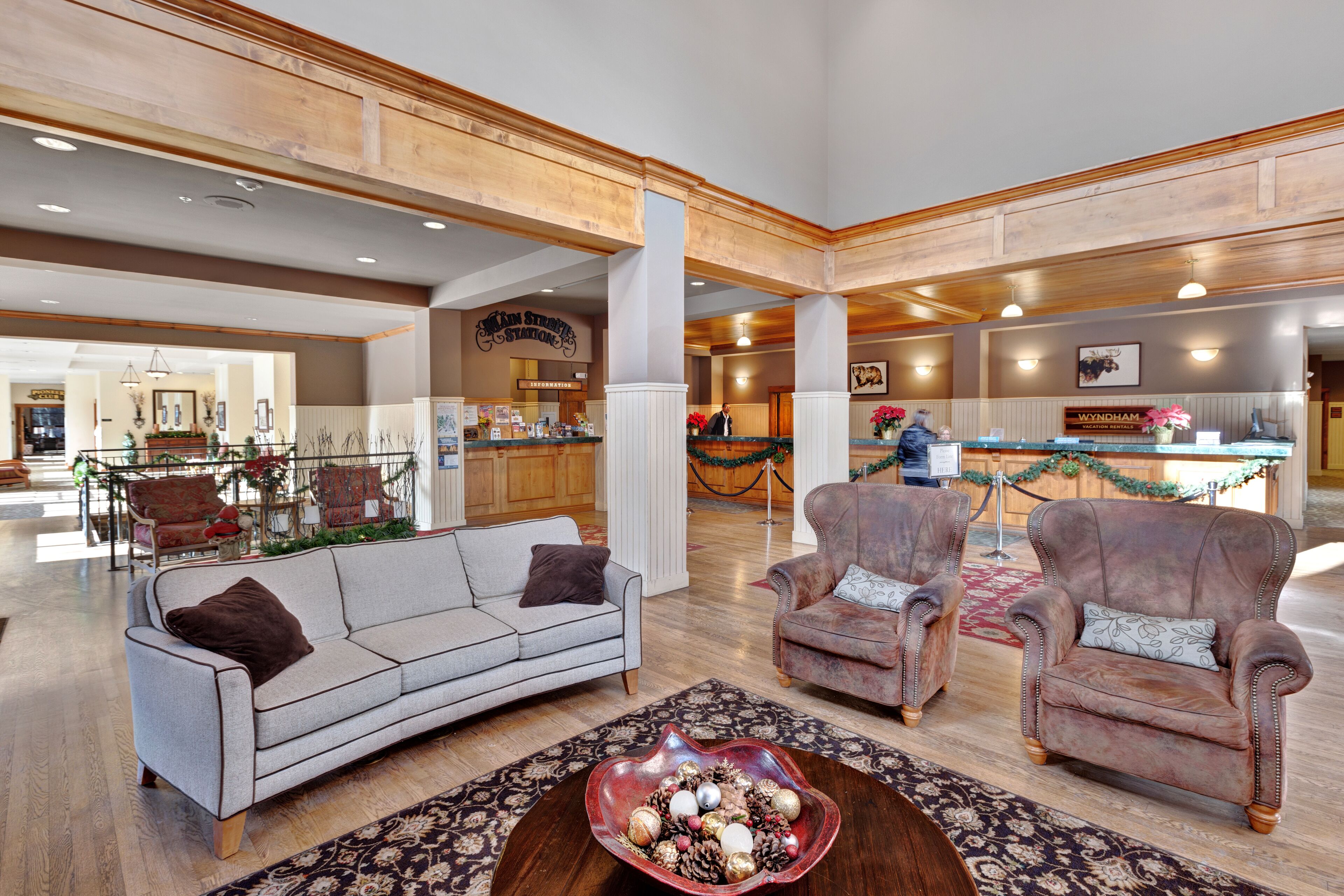 A spacious lobby with a reception desk, two armchairs, a sofa, and a decorative bowl on a wooden coffee table.