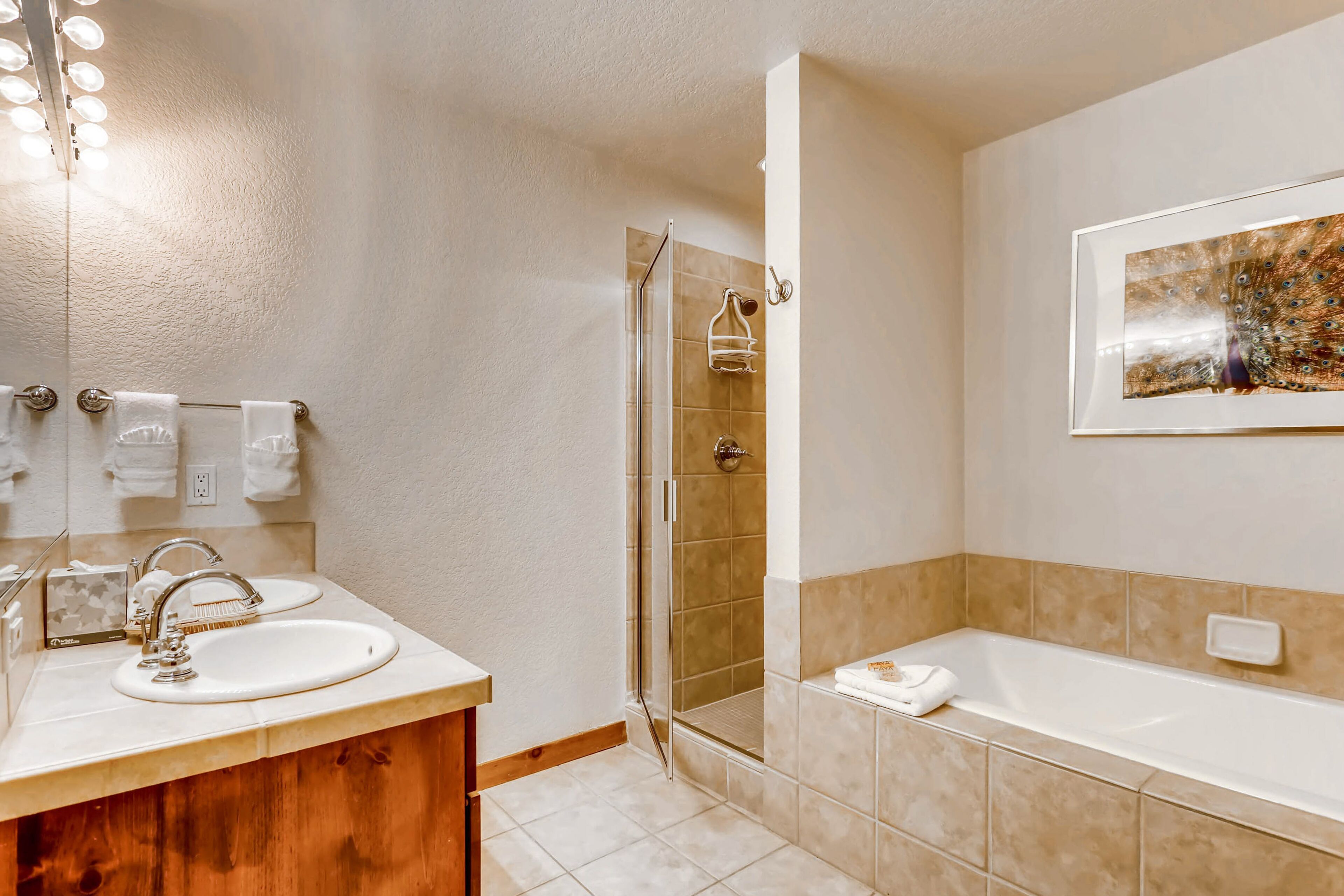 A bathroom with a sink, mirror, shower, and bathtub.