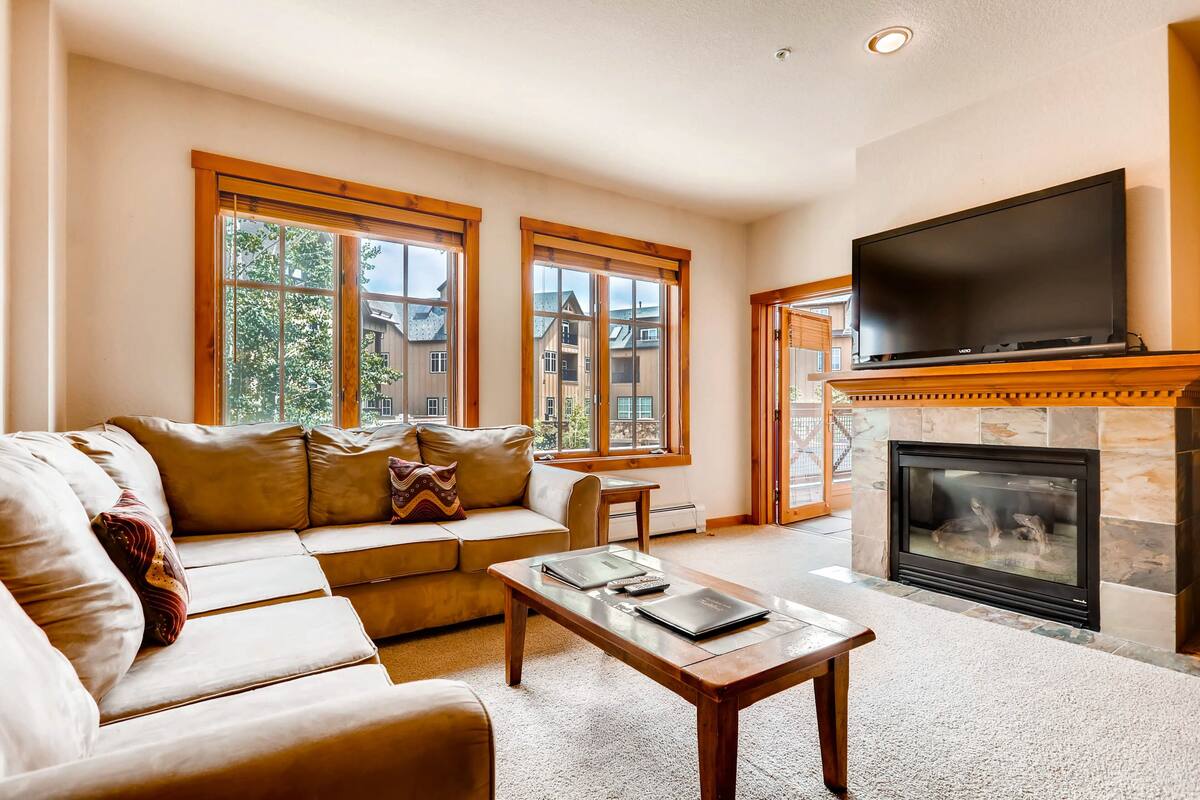 A living room with a sofa, coffee table, fireplace, and a TV.