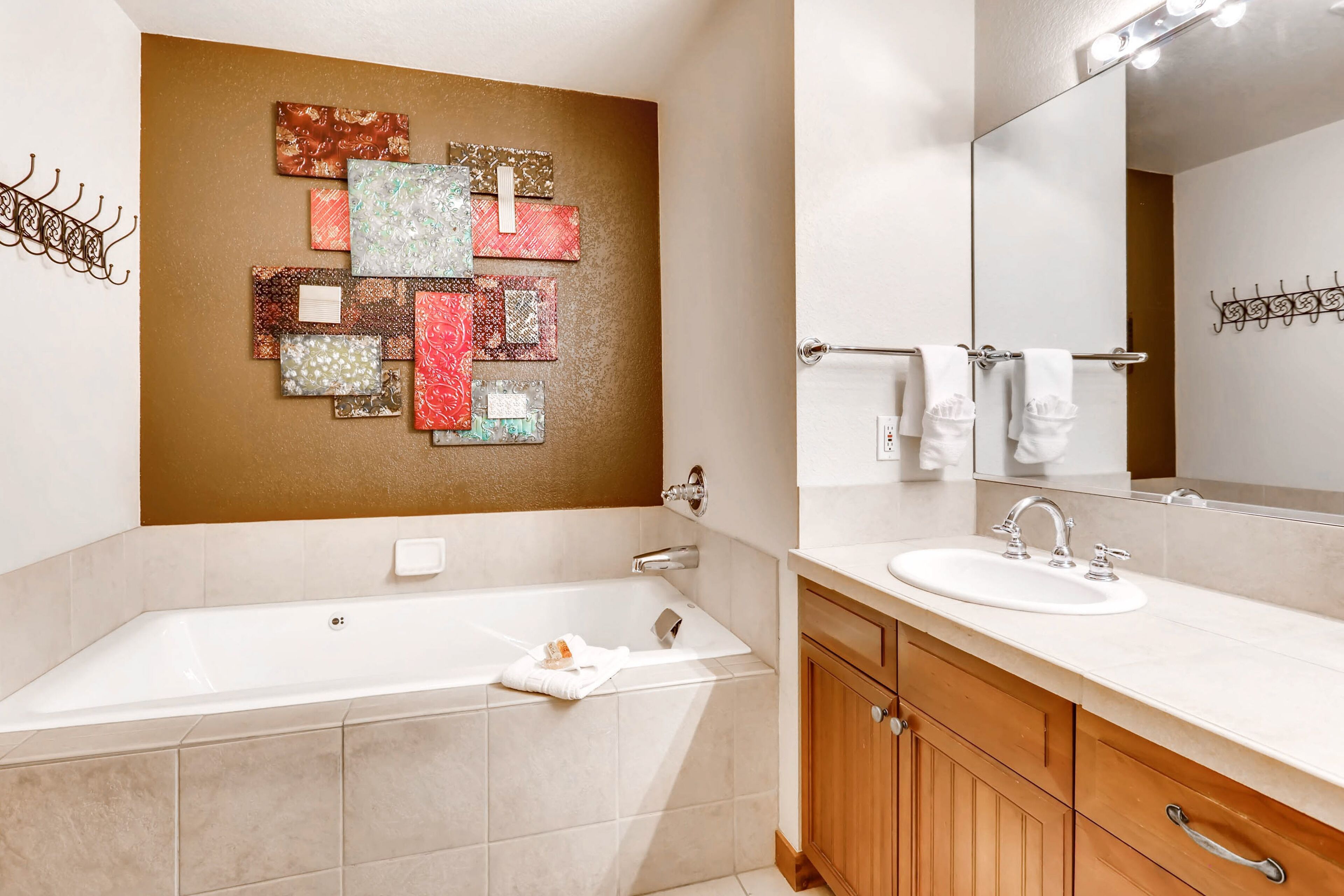 A modern bathroom with a large bathtub, a vanity with a sink, and a wall-mounted mirror.