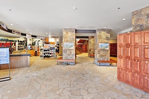 A spacious lobby with stone flooring, a shoe display, and wooden cabinets.