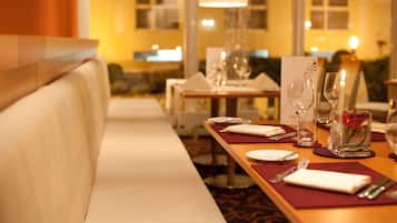 Ein Restaurantambiente mit einem langen Tisch, gedeckt für ein Essen, einschließlich Tellern, Besteck und Gläsern.