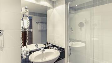 A modern bathroom with a glass-enclosed shower, a white sink, and a mirror.