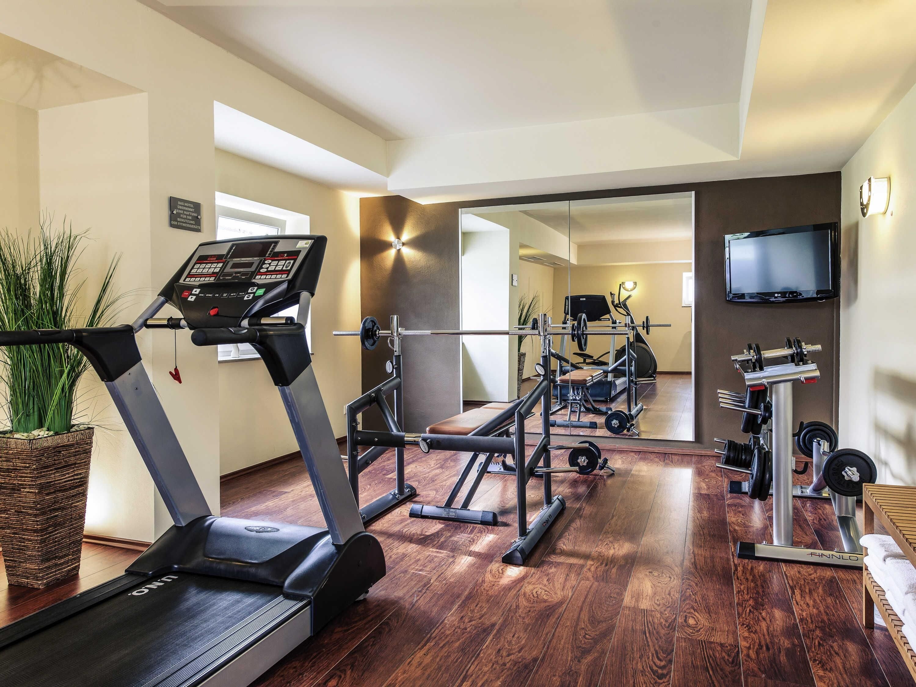 A gym with a treadmill, weight bench, and various exercise equipment.