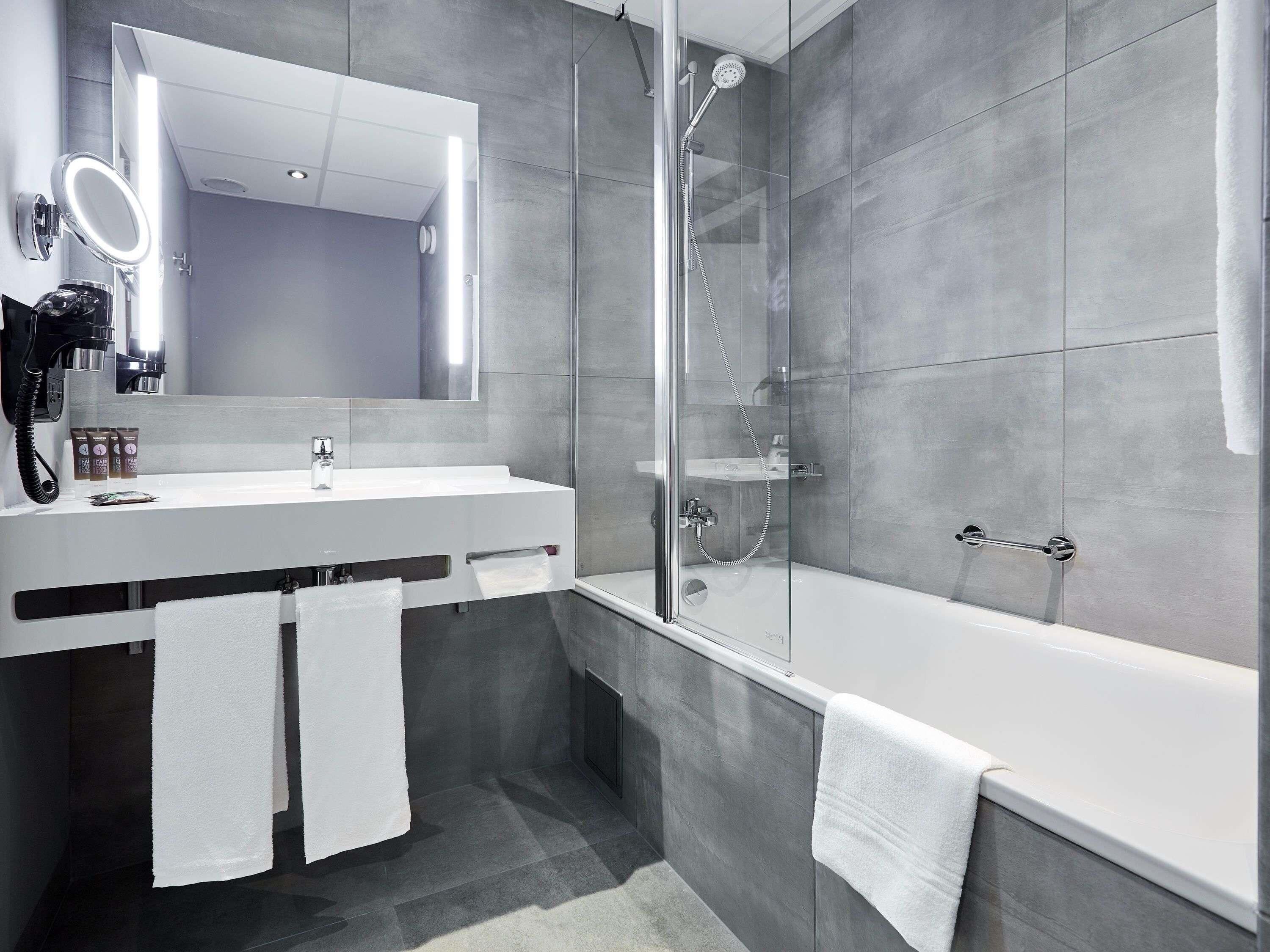 A modern bathroom with a glass-enclosed shower, a white sink, and a large mirror.