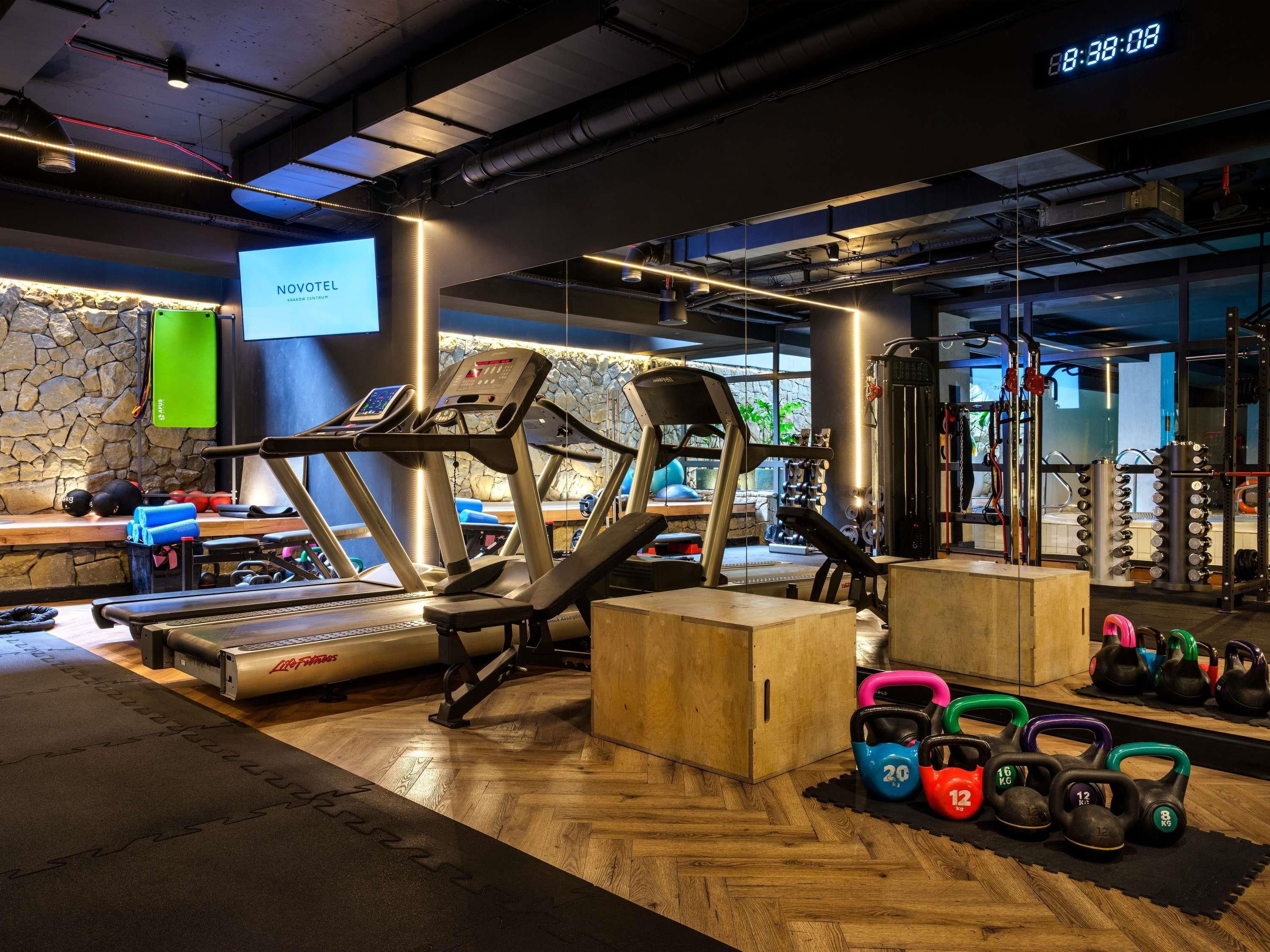 A gym with treadmills, a weight bench, kettlebells, and a digital clock.