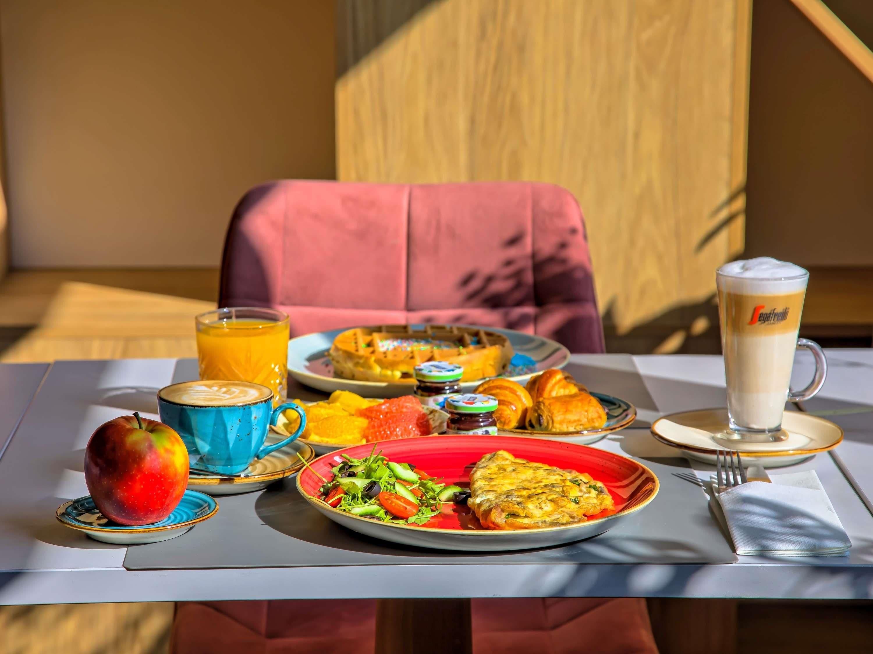 A breakfast setting with a plate of food, a glass of orange juice, a cup of coffee, and a croissant.