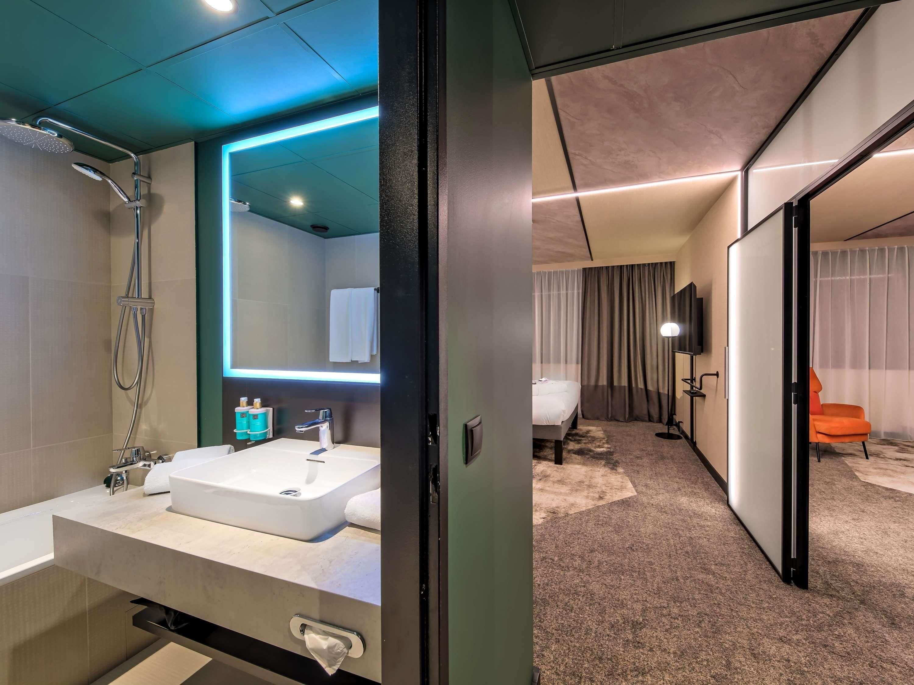 Une salle de bain moderne avec un grand miroir, une baignoire et une douche.