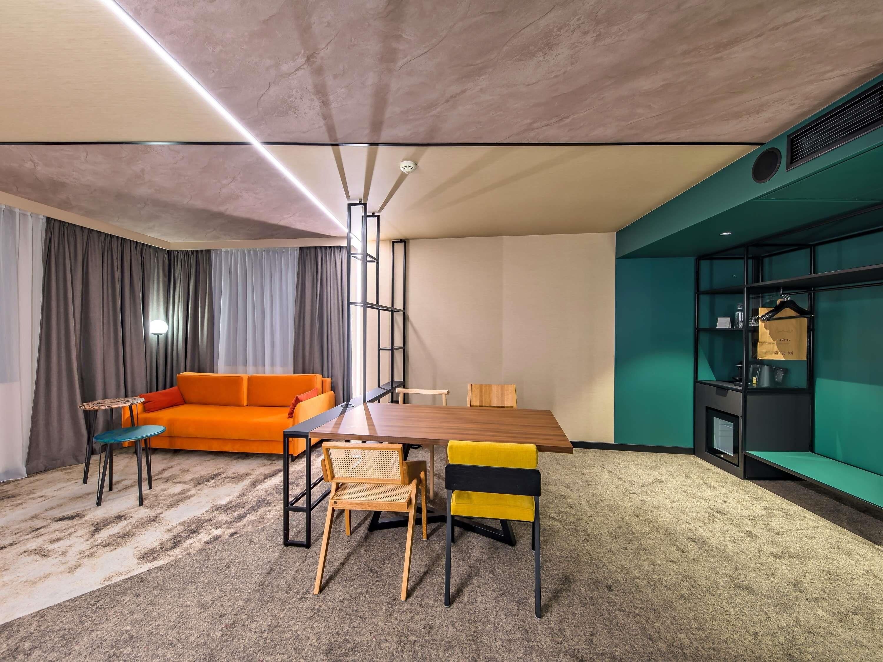 Una habitación moderna con una mesa de comedor de madera, sillas, un sofá y una pared decorada en color verde.