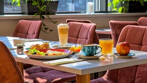 A dining table with a meal, drinks, and a potted plant in a restaurant. - Novotel Krakow Centrum (Kraków)