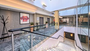 A modern interior with a glass railing, a framed jersey, and potted plants. - Novotel Krakow Centrum (Kraków)