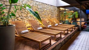 A spa area with wooden loungers, a stone wall, and potted plants. - Novotel Krakow Centrum (Kraków)