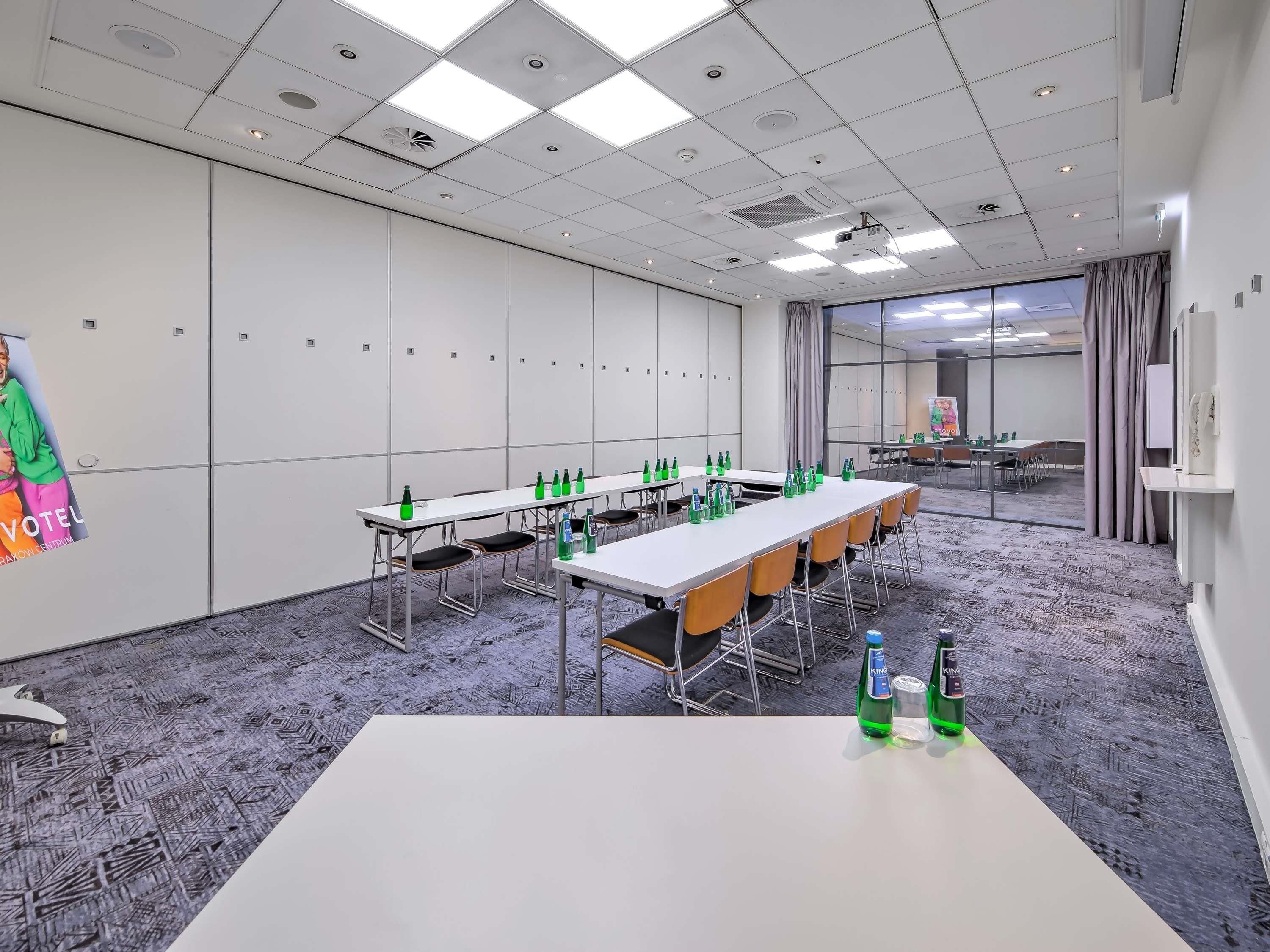 A conference room with tables, chairs, and bottled water.