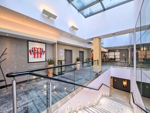 A modern hotel lobby with a glass railing, a staircase, and a framed sports jersey on the wall. - Novotel Krakow Centrum (Kraków)