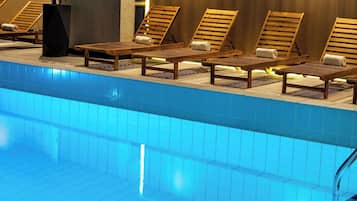 Una piscina con tumbonas de madera y una planta en maceta.