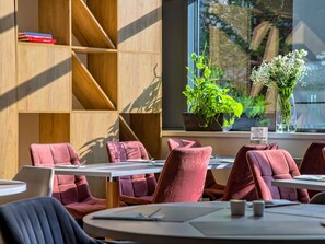 A modern interior with wooden shelving, red upholstered chairs, and a view of greenery through a window. - Novotel Krakow Centrum (Kraków)