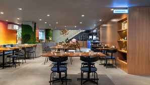 A modern restaurant with multiple seating areas, including a bar and a counter.