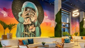 A modern lounge area with a mural, seating, and plants.