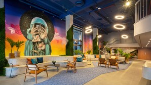 A modern lobby with a mural, seating areas, and a staircase.