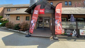 A hotel entrance with 'ibis' branding, a brick facade, and a clear sky. - ibis Brussels Waterloo (Waterloo)