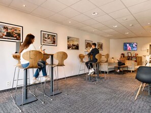 A modern interior with bar stools, a sofa, and a television. - ibis Brussels Waterloo (Waterloo)