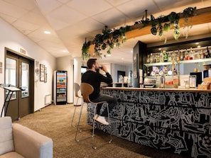 A bar area with a counter, seating, and a beverage dispenser. - ibis Brussels Waterloo (Waterloo)