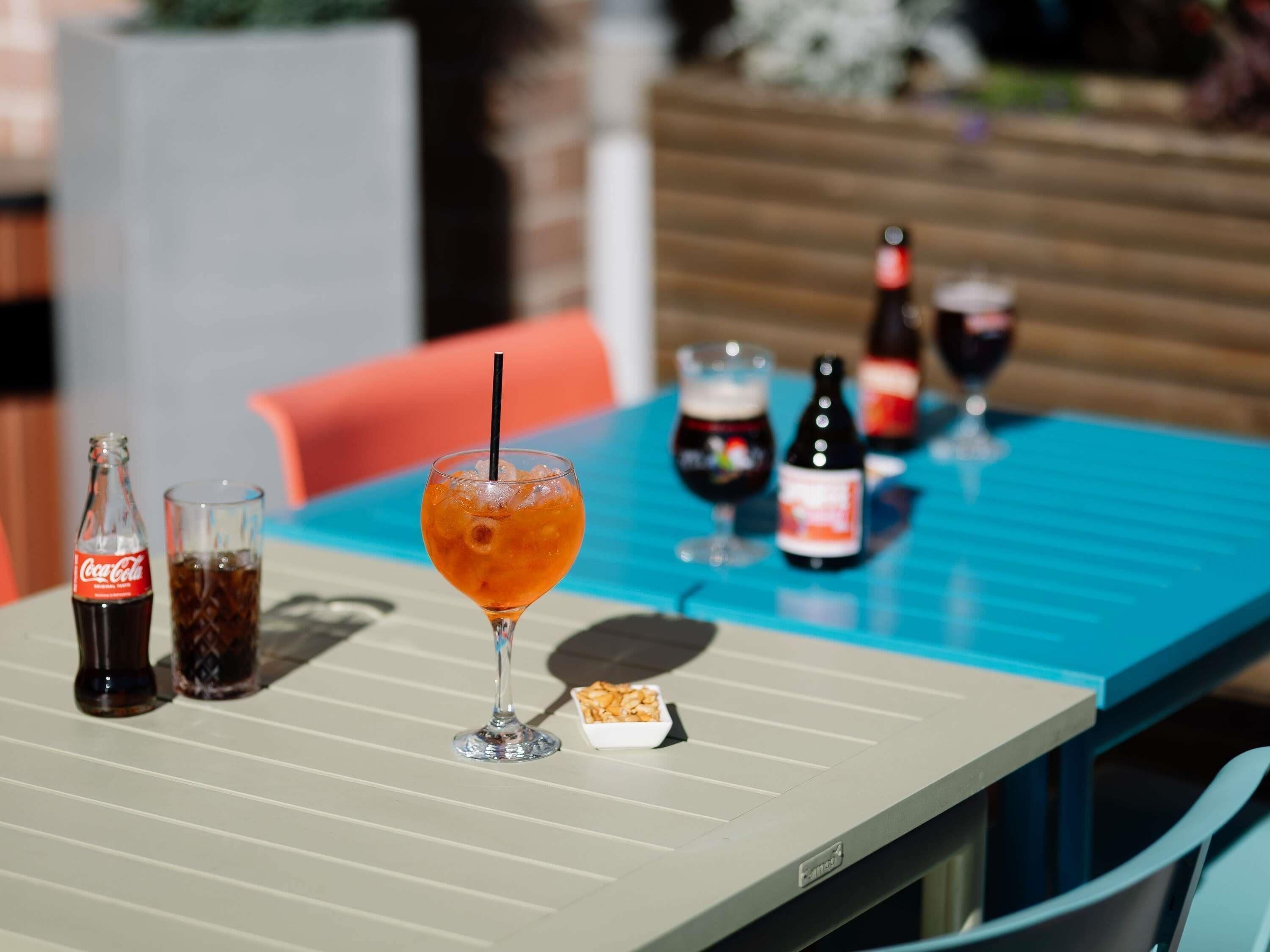 A table with a drink, a bottle, and glasses.
