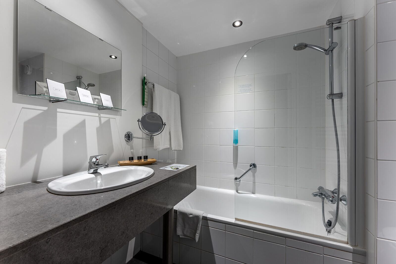 A modern bathroom with a white sink, a mirror, a glass shower enclosure, and a bathtub.