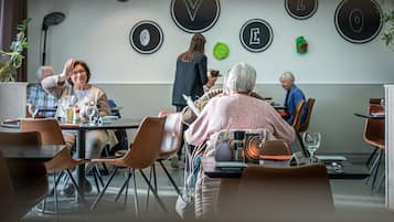 A modern dining area with round tables, chairs, and a wall with circular signs.
