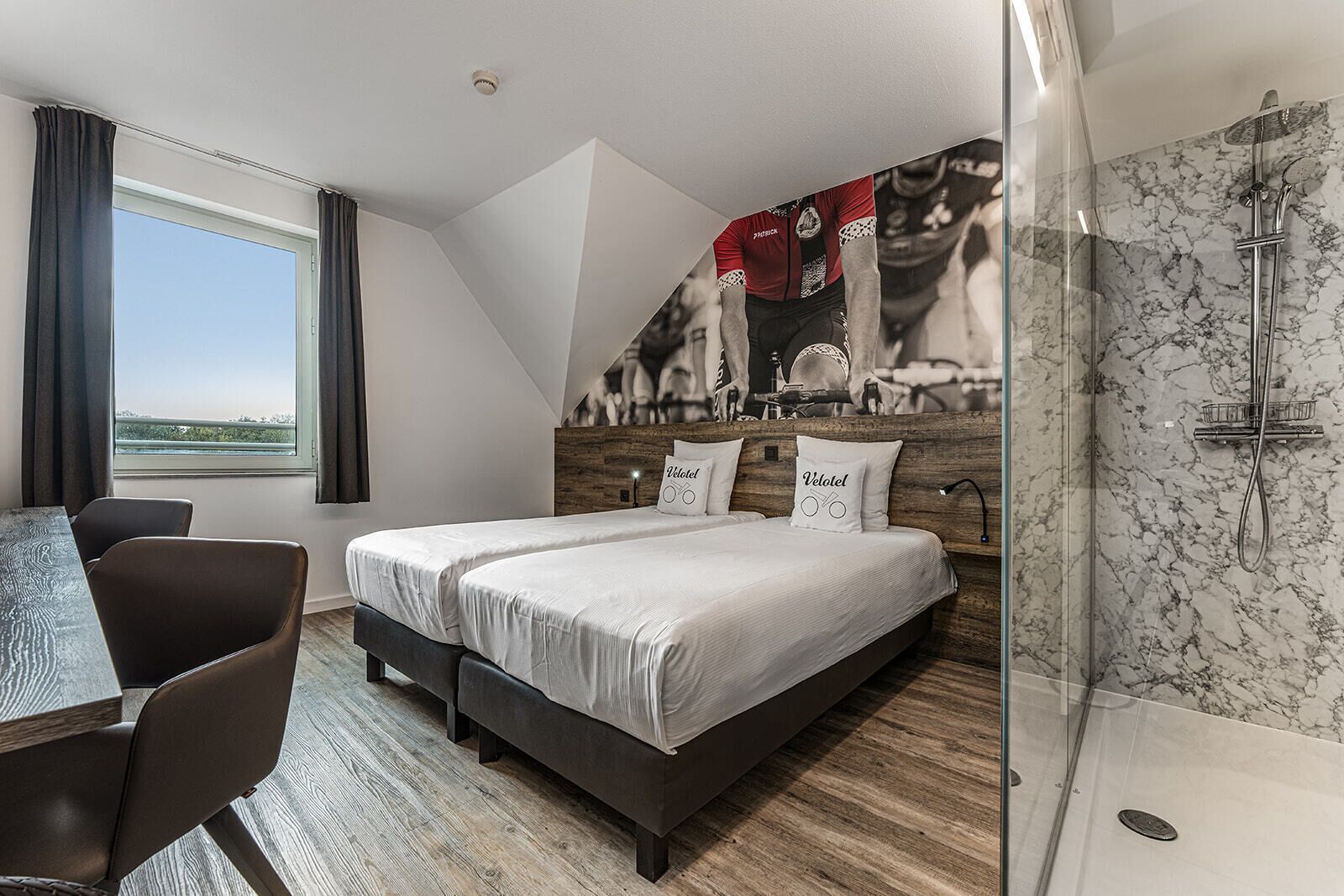 Una habitación de hotel moderna con una cama grande, un escritorio y una ducha.