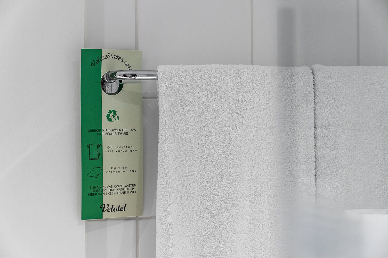 A white towel hanging on a metal towel rack in a bathroom.