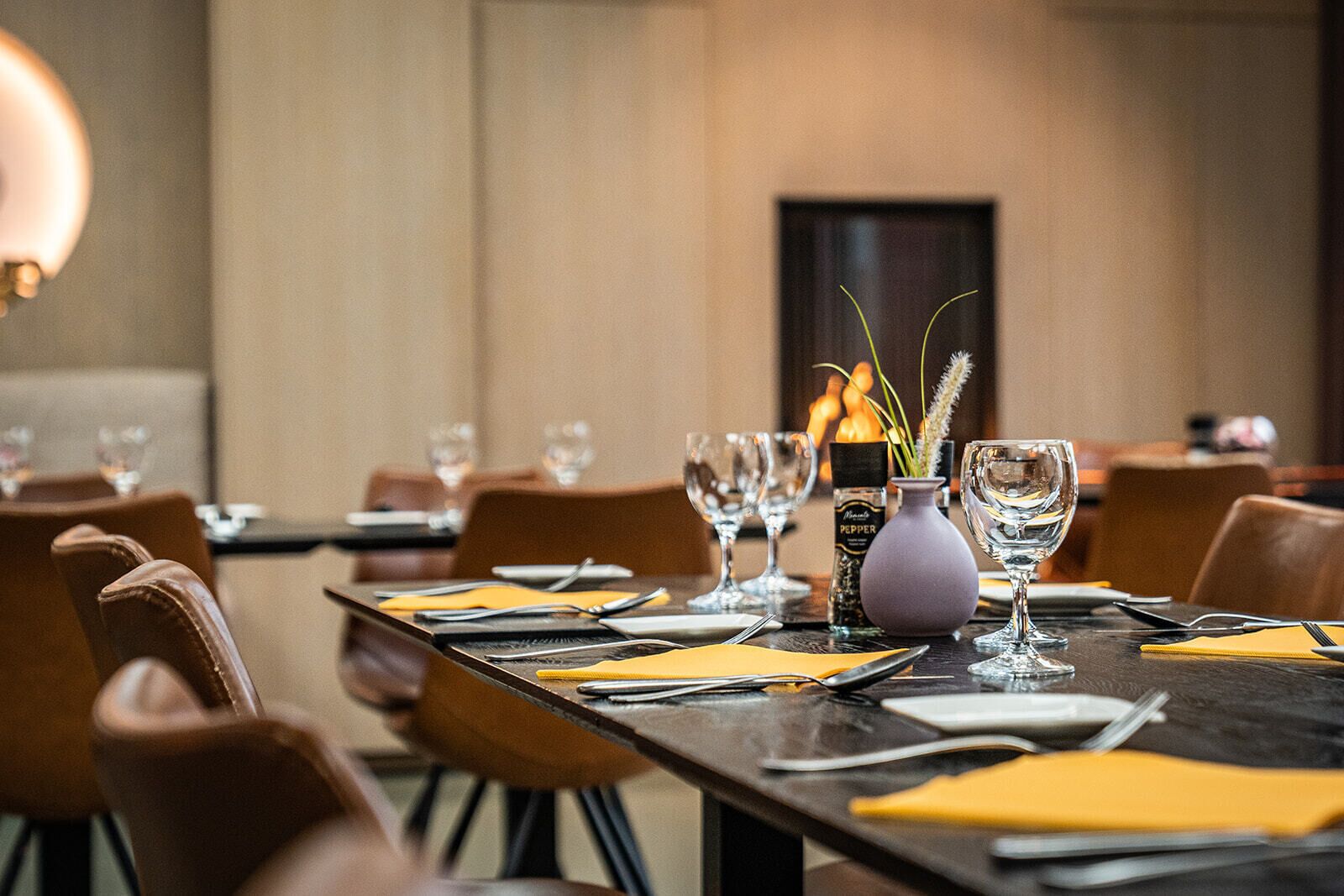 A dining area with tables set for a meal, including wine glasses, cutlery, and napkins.