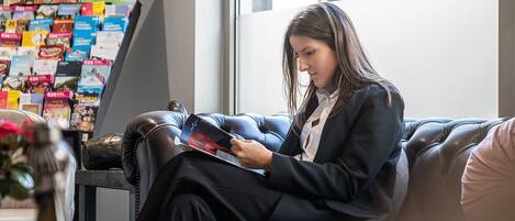 A person sitting on a leather couch in a room with a large poster of a park and a window.