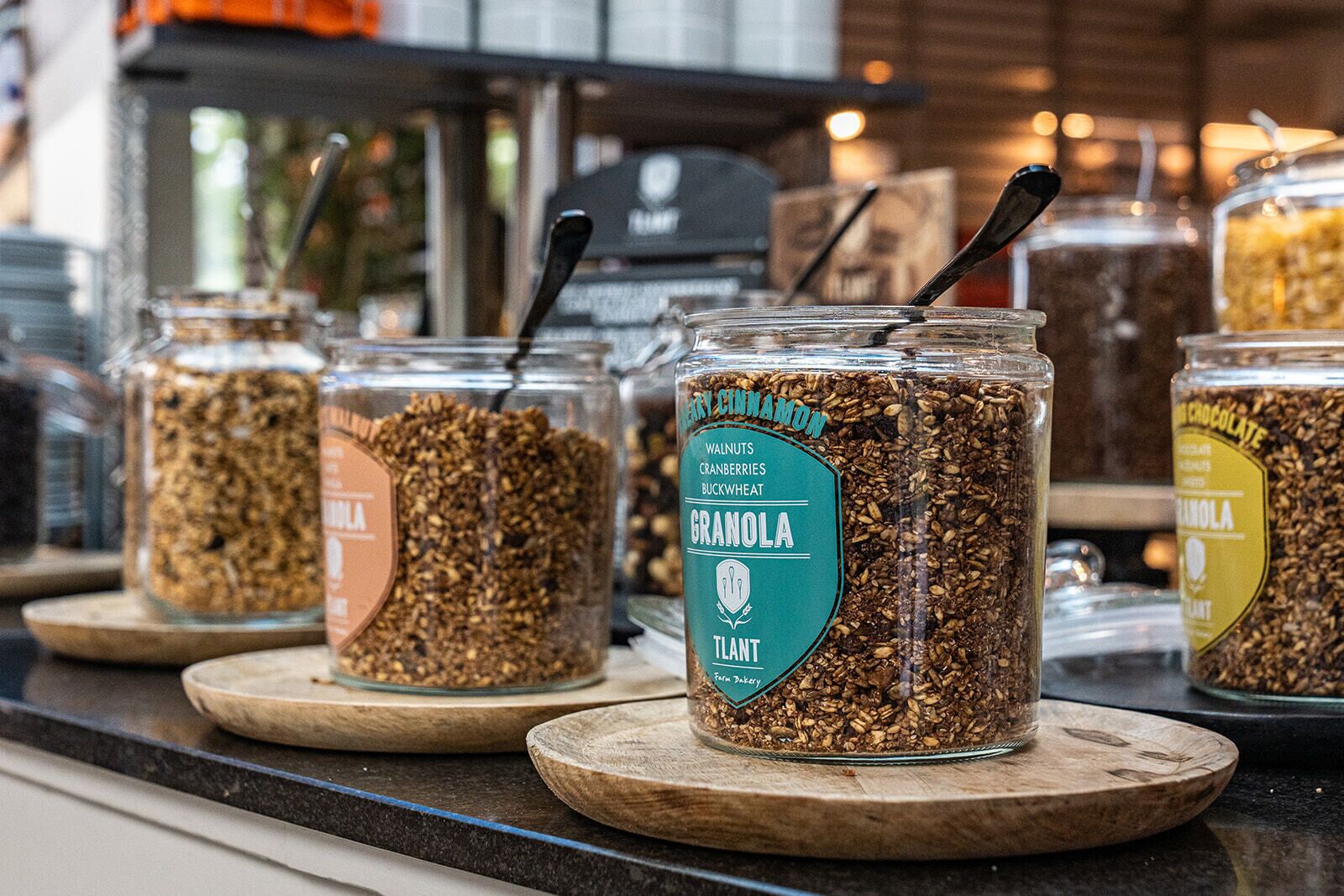 Une sélection de pots de granola présentés sur des planches en bois dans un magasin.