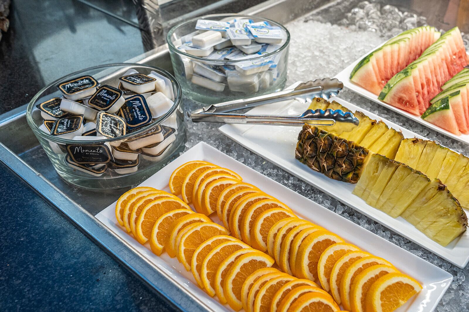 Ein Buffet mit Orangenscheiben, Ananas, Wassermelone und Schokoladenriegeln.