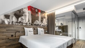 A modern hotel bedroom with a large bed, wooden headboard, and a cycling-themed wall mural. - Velotel Brugge (Bruges)