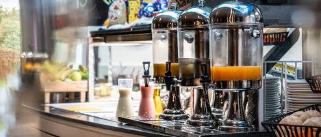 A coffee station with multiple dispensers, a milk pitcher, and a basket of pastries.