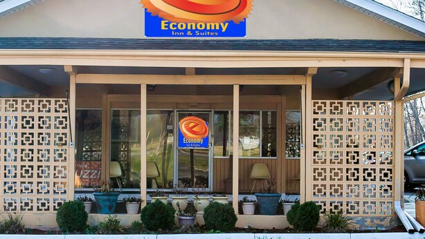Um hotel com uma placa indicando 'Economy Inn & Suites' e um logotipo com um sol e uma engrenagem.