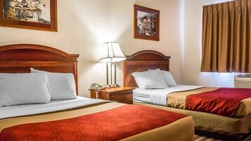 Habitació d'hotel amb dos llits, una tauleta de nit amb una làmpada i dos quadres a la paret.
