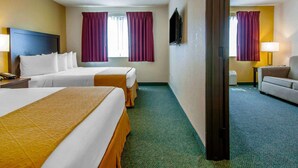A hotel room with two beds, a desk, a chair, a TV, and a window with curtains. - Quality Inn & Suites Springfield - Eugene North (Springfield)