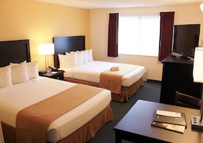 A hotel room with two beds, a desk, a TV, and a window with curtains. - Quality Inn & Suites Springfield - Eugene North (Springfield)