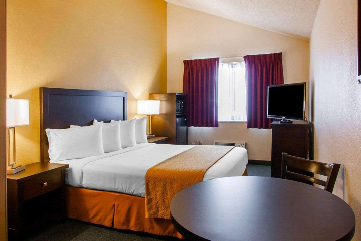 A hotel room with a bed, bedside tables, a television, a desk, and a chair.